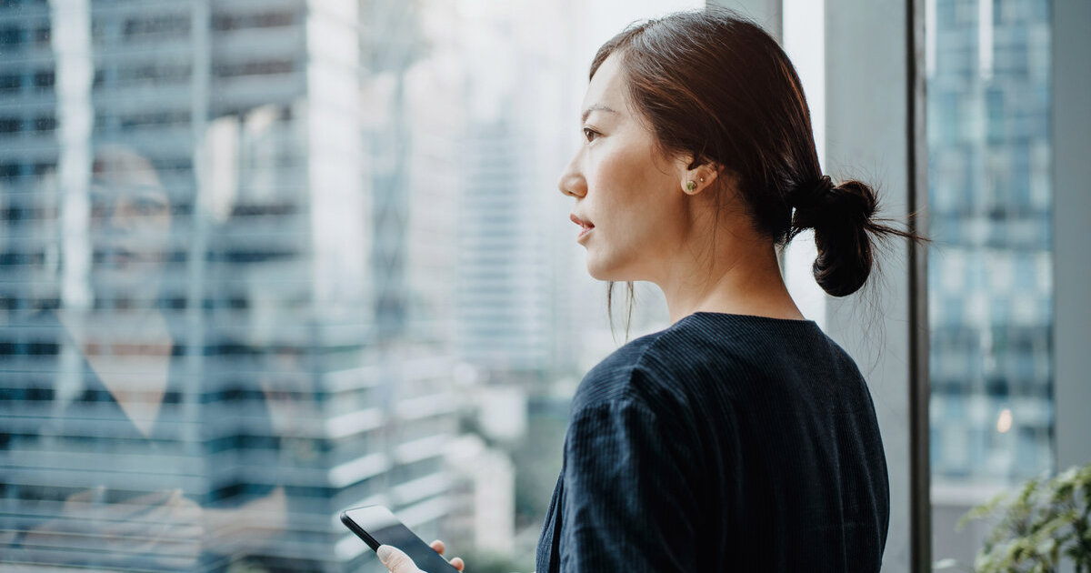 A person holding a phone looking out the window