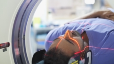 Person lying in a scanner with a red light across their face