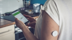 Image of person with glucose patch looking at a smartphone