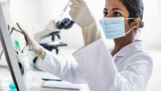Person wearing mask holding test tube