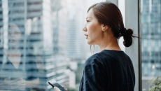 A person holding a phone looking out the window