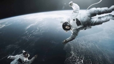 Two astronauts floating above earth in space reaching for each other