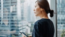 Person standing inside a building looking out a glass window at a big city