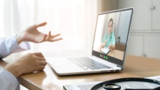 Person in lab coat talking with hands to nurse on laptop Person in lab coat talking with hands to nurse on laptop