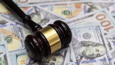 A gavel lying on a pile of hundred dollar bills.