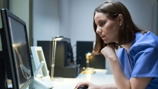 A doctor looking at imaging results on a desktop computer.