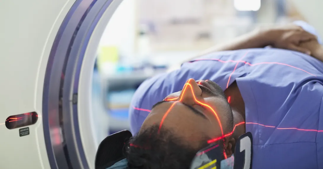 
  Person being rolled into an imaging machine with red lasers scanning their head 
