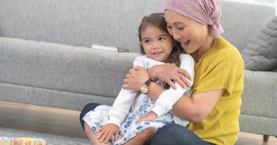 
  Person and child embracing while sitting on the floor

