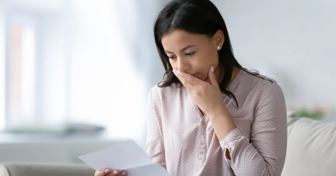
  Person with their mouth covered looking at a piece of paper
