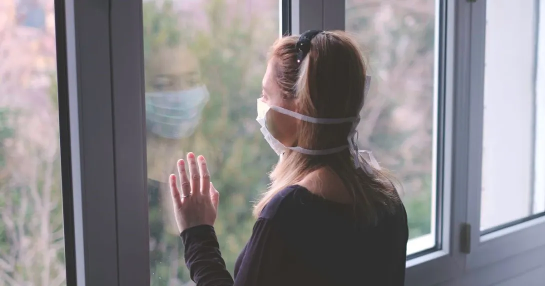 Person Wearing mask looking out window Person wearing mask looking out window
