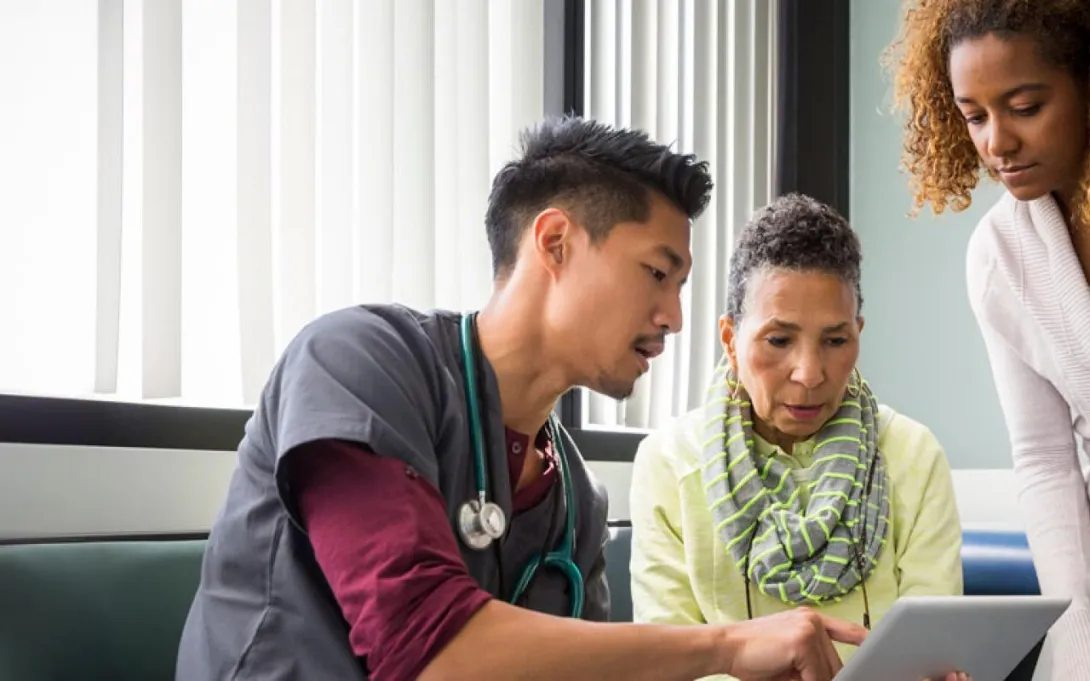 Healthcare professional discusses with two people over a laptop