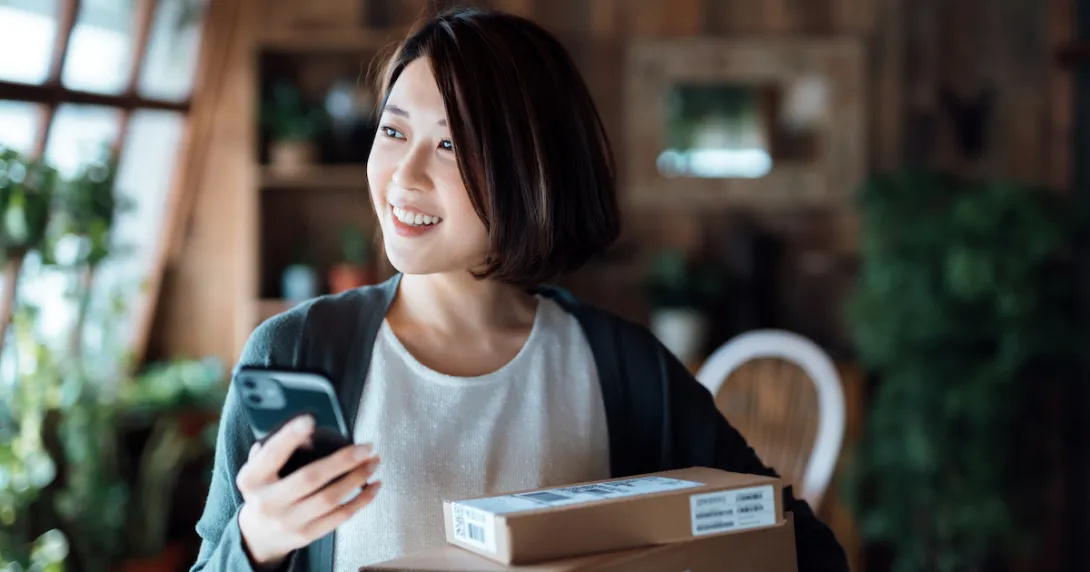 Person smiling while in their home and holding a phone with boxes around them