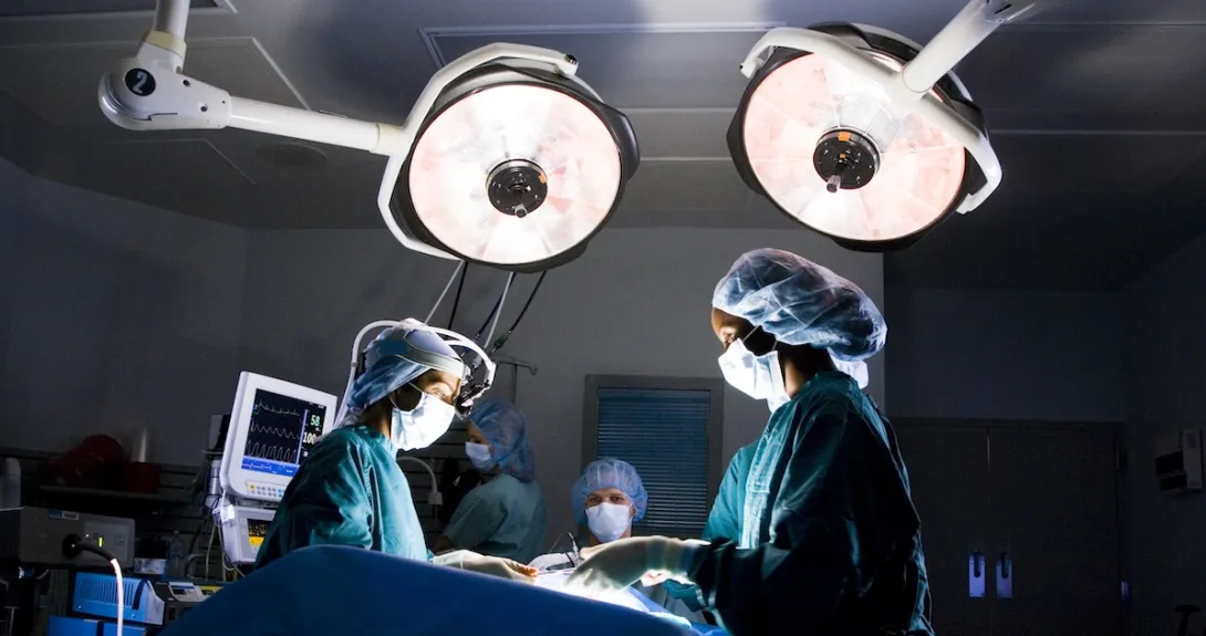 Surgeons standing around an operating table performing surgery
