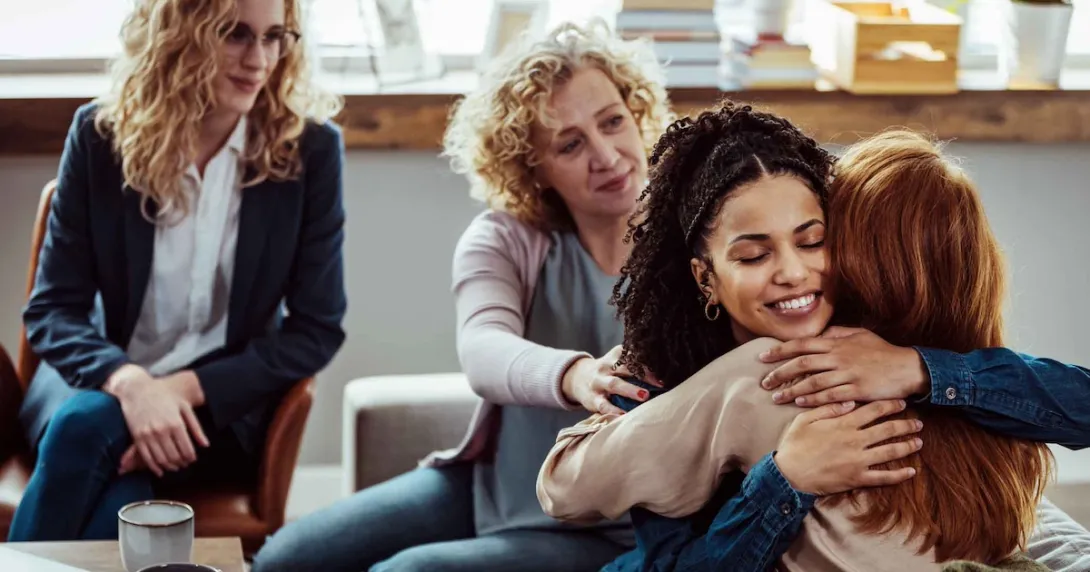 Group therapy session with four people sitting in chairs and two of of them hugging each other Group therapy session with four people sitting in chairs and two of of them hugging each other