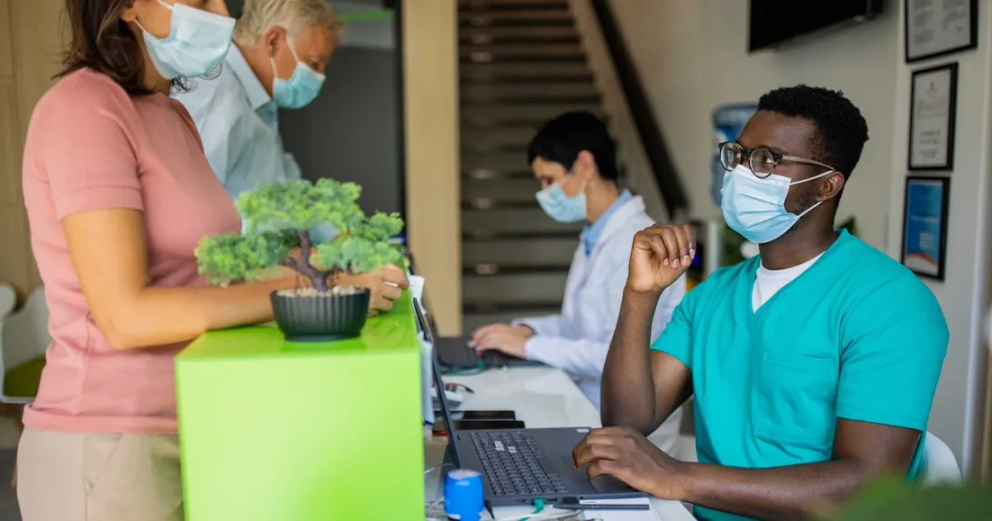 Healthcare providers sitting at a table with two people standing up on the other side Healthcare providers sitting at a table with two people standing up on the other side