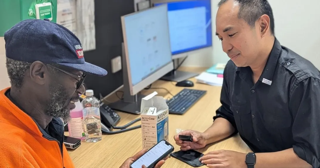 A patient with diabetes being assisted in using a mobile app to track their blood glucose level