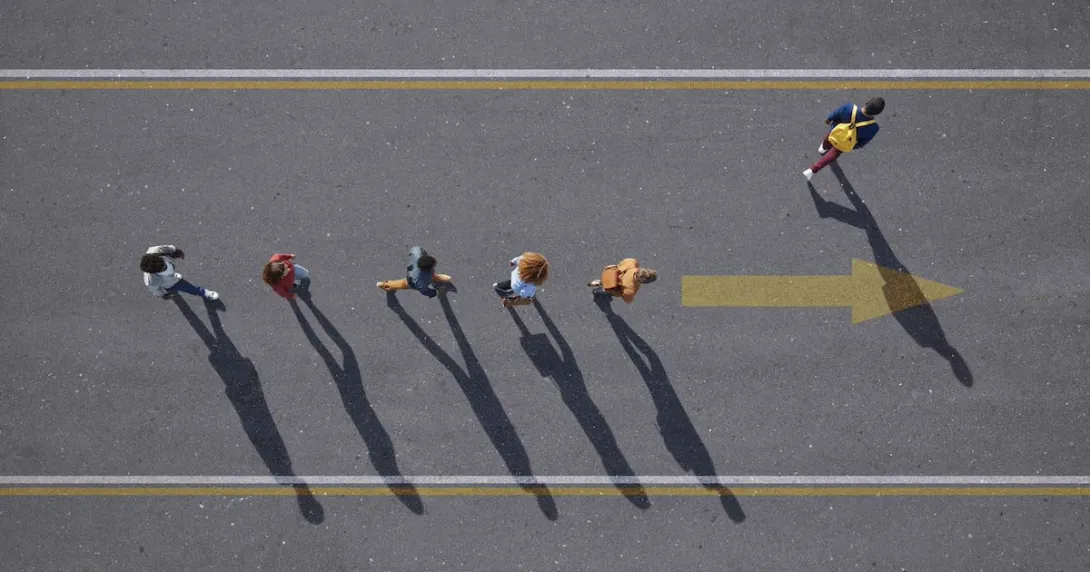 People walking in a line with one person walking elsewhere