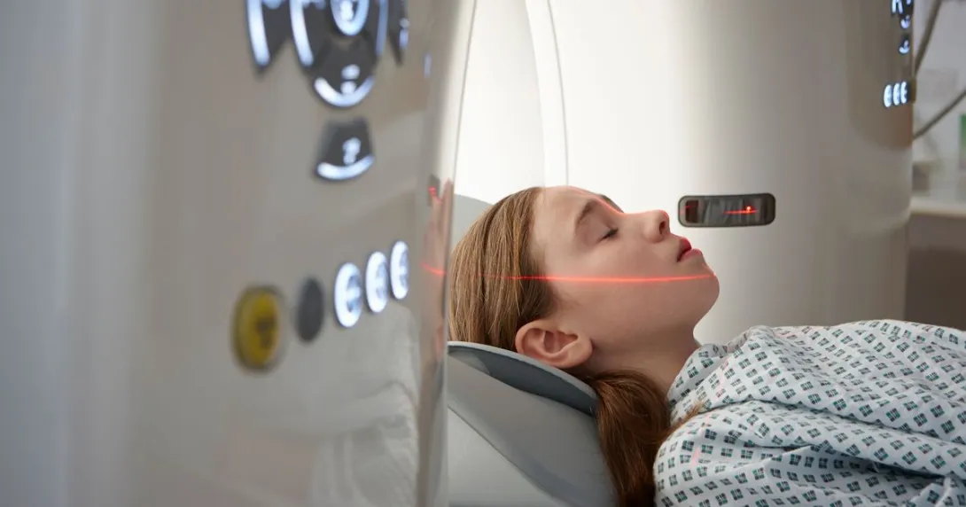Person lying just outside an MRI machine with a red scanning light on their face