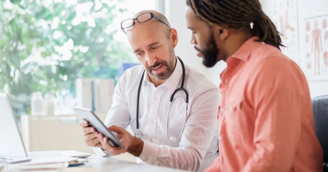 Healthcare provider sitting next to a person while both are looking at a tablet