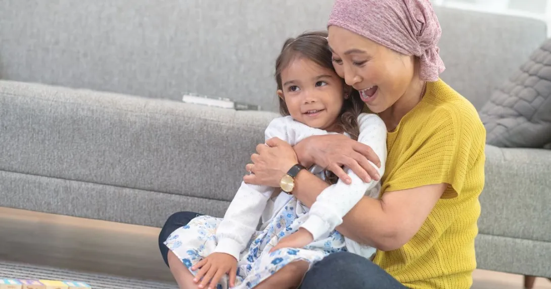Person sitting on the floor holding another person in their hands while wearing a head scarf
Person sitting on the floor holding another person in their hands while wearing a head scarf