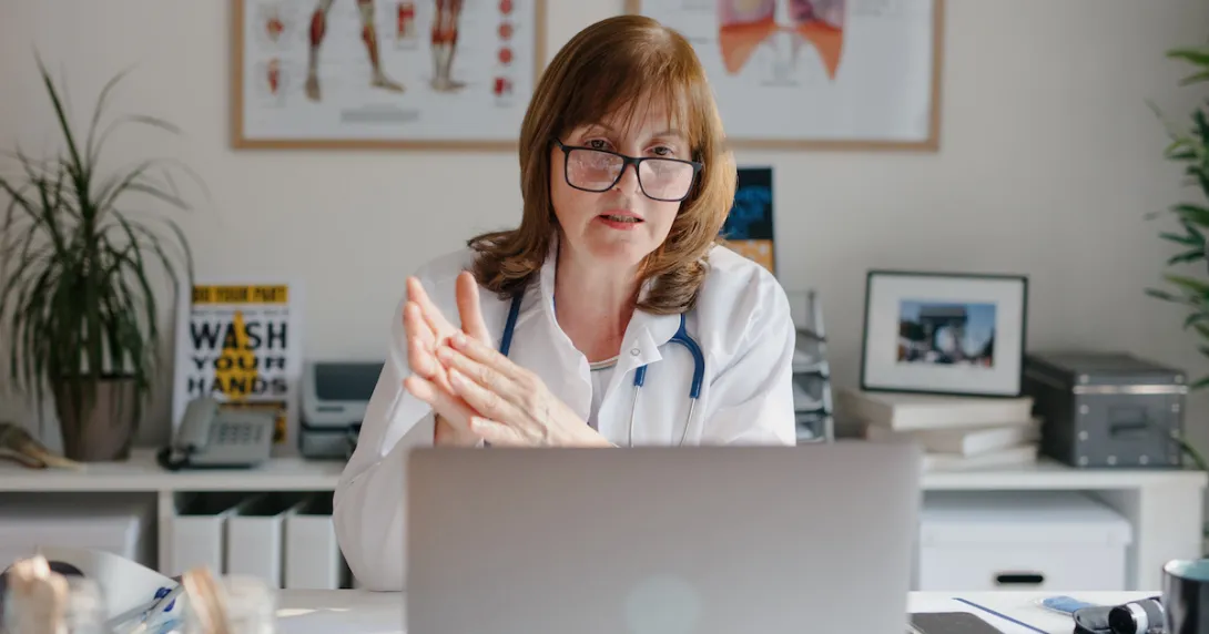 Healthcare professional sitting at a desk looking at a computer