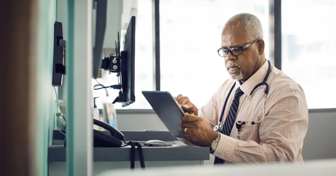 Healthcare provider at a desk scrolling through a tablet