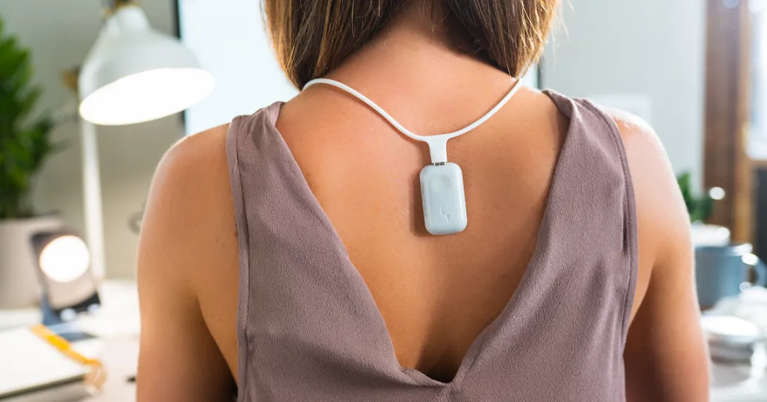 Person wearing the Upright GO S on the necklace while working at a desk