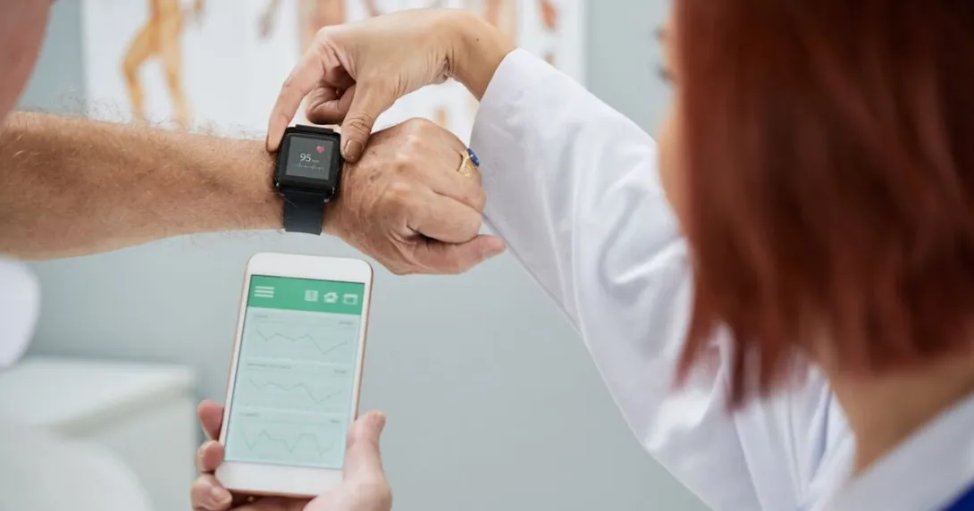 A doctor showing patient how to synchronize health app in smartphone and smartwatch