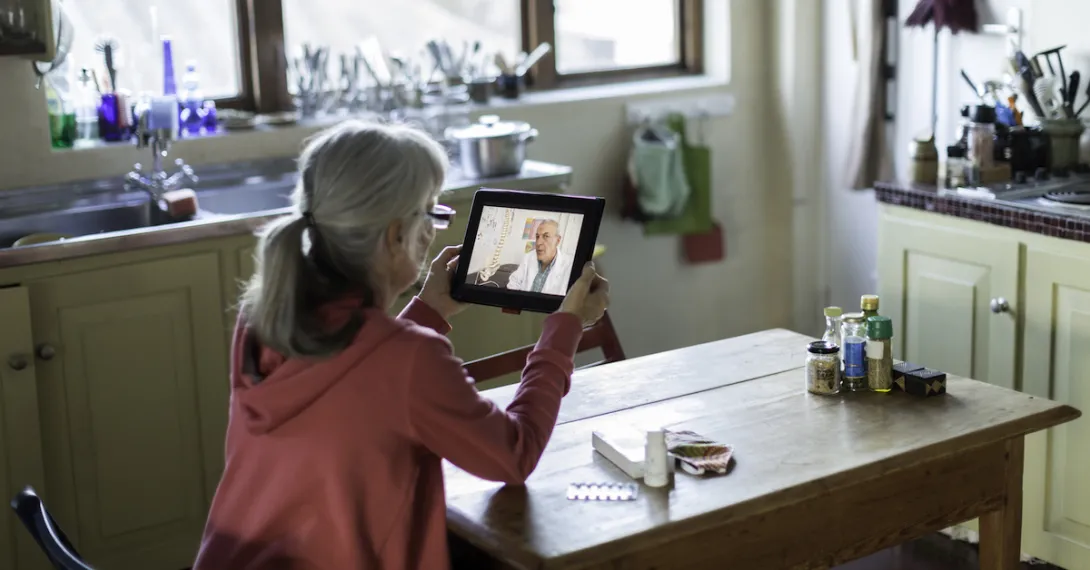 A woman talking with a doctor on her tablet.