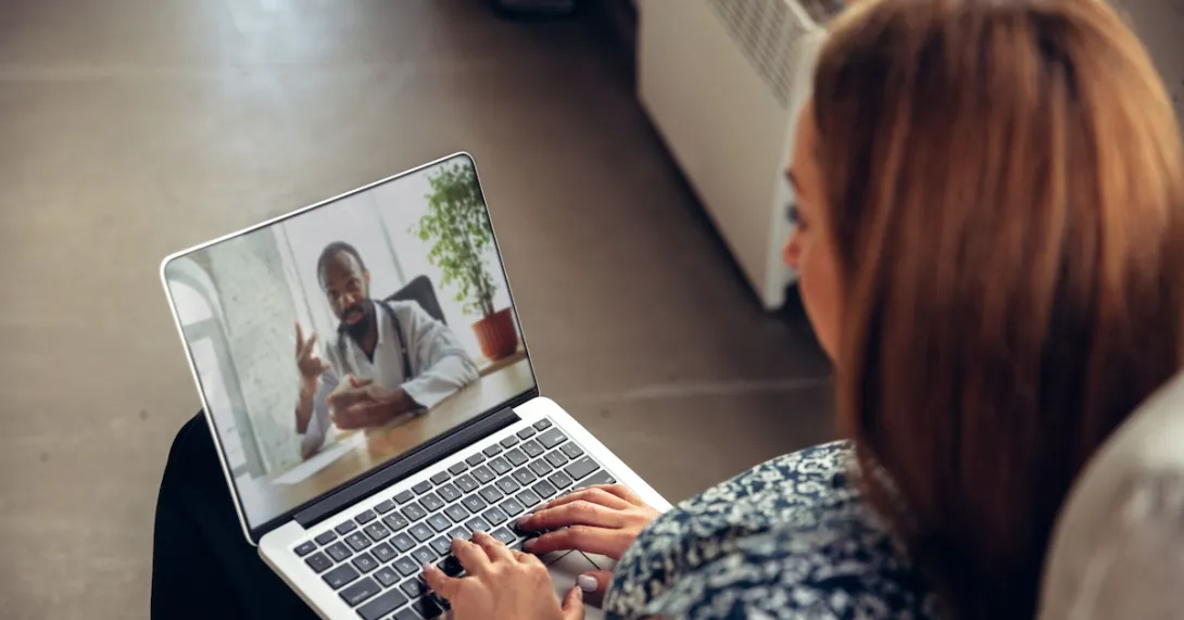 A woman talking to a doctor through a video chat on her laptop.