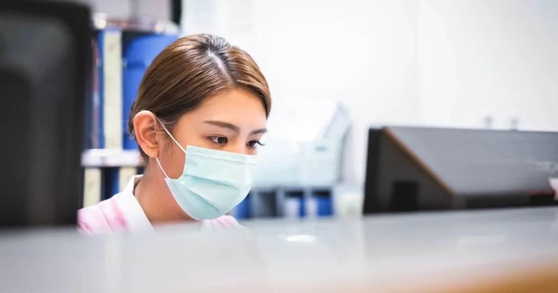 A nurse wearing a surgical mask working at reception A nurse wearing a surgical mask working at reception