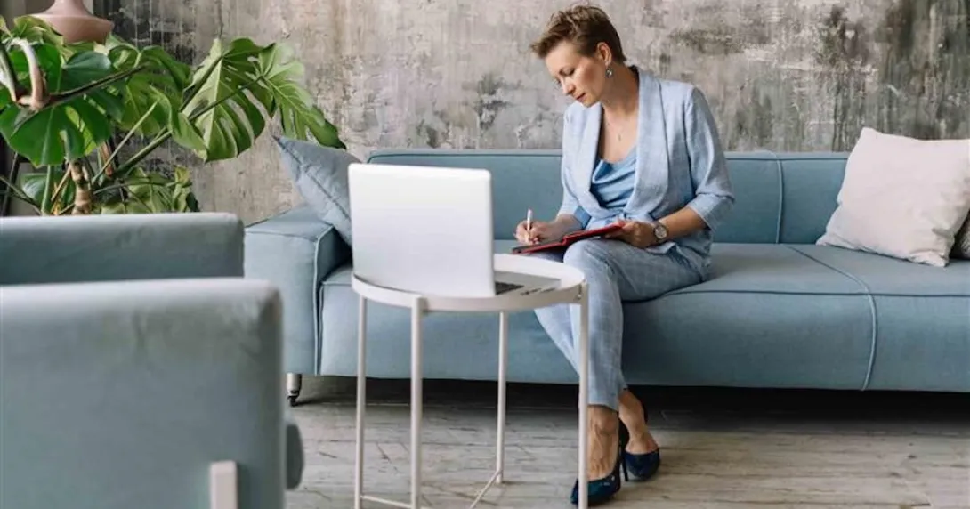 Person sitting on a couch while looking at a computer Person sitting on a couch while looking at a computer