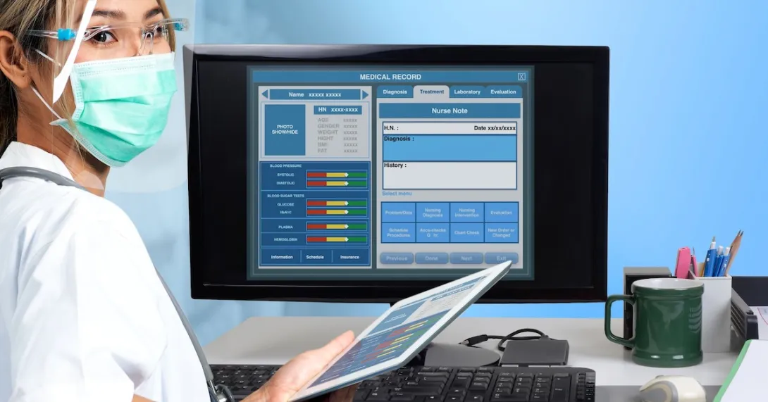 Healthcare professional standing in front of a computer with an EHR on the screen Healthcare professional standing in front of a computer with an EHR on the screen