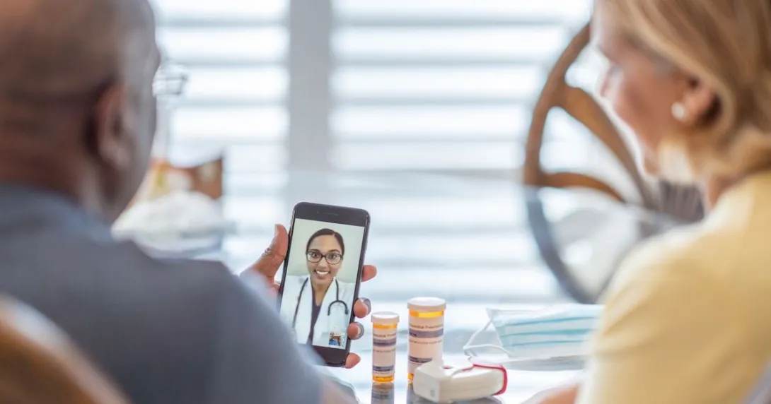 A couple talking to a provider through a video chat on a smartphone. A couple talking to a provider through a video chat on a smartphone.