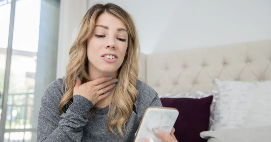 A person talking on a video chat on a phone about a sore throat A person talking on a video chat on a phone about a sore throat